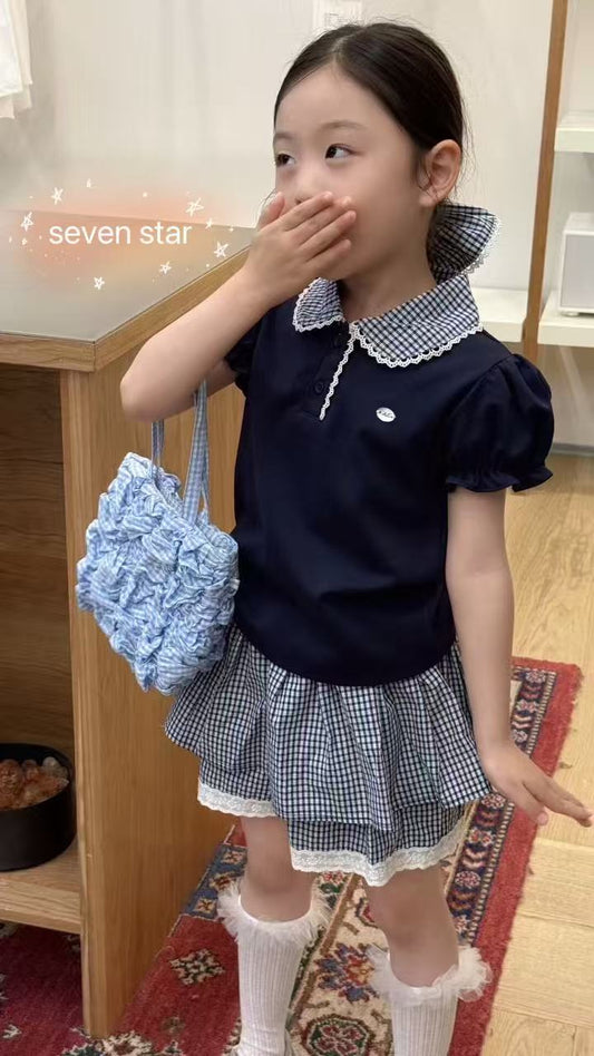 Young girl in a navy dress with white checkered details.